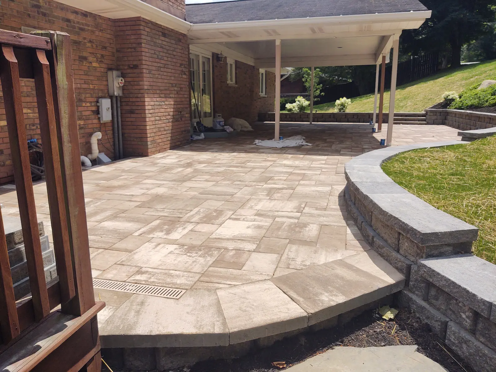 Covered patio connected to a curved retaining wall by Dave's Landscaping