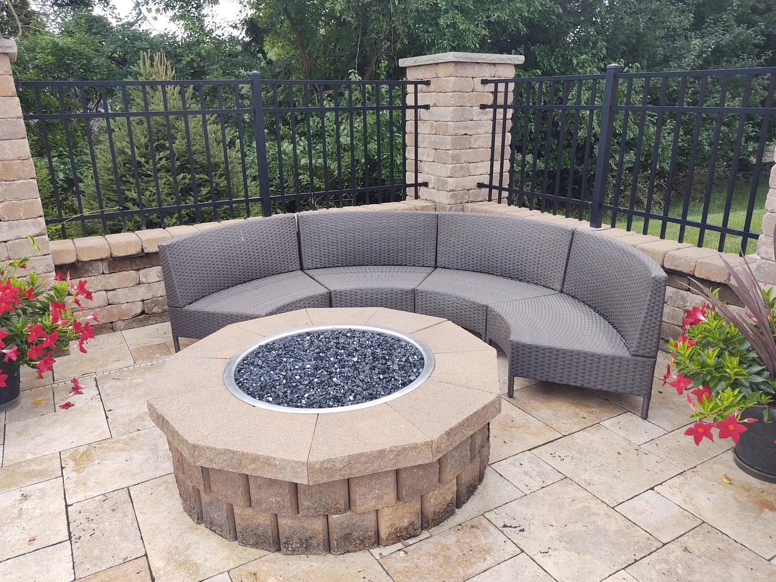 Curved sectional and gas fire pit inside a private courtyard by Dave's Landscaping