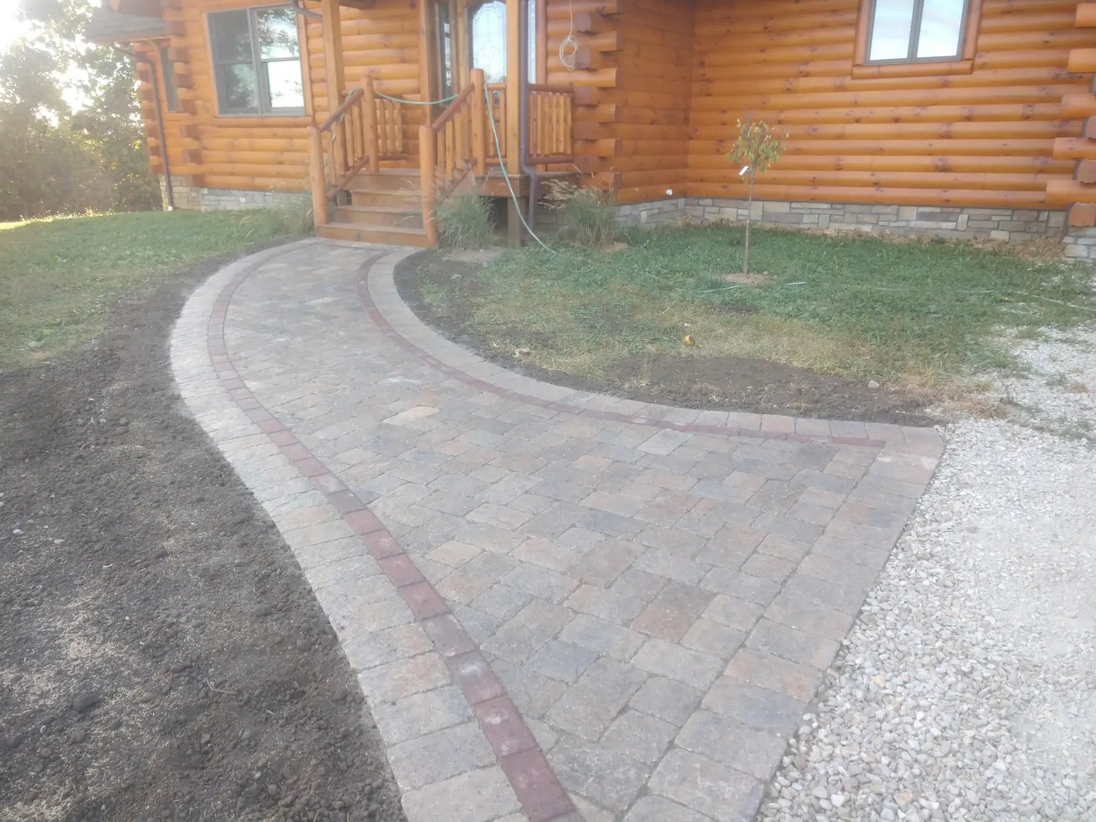 Curved paver walk leading to a log-home entry by Dave's Landscaping