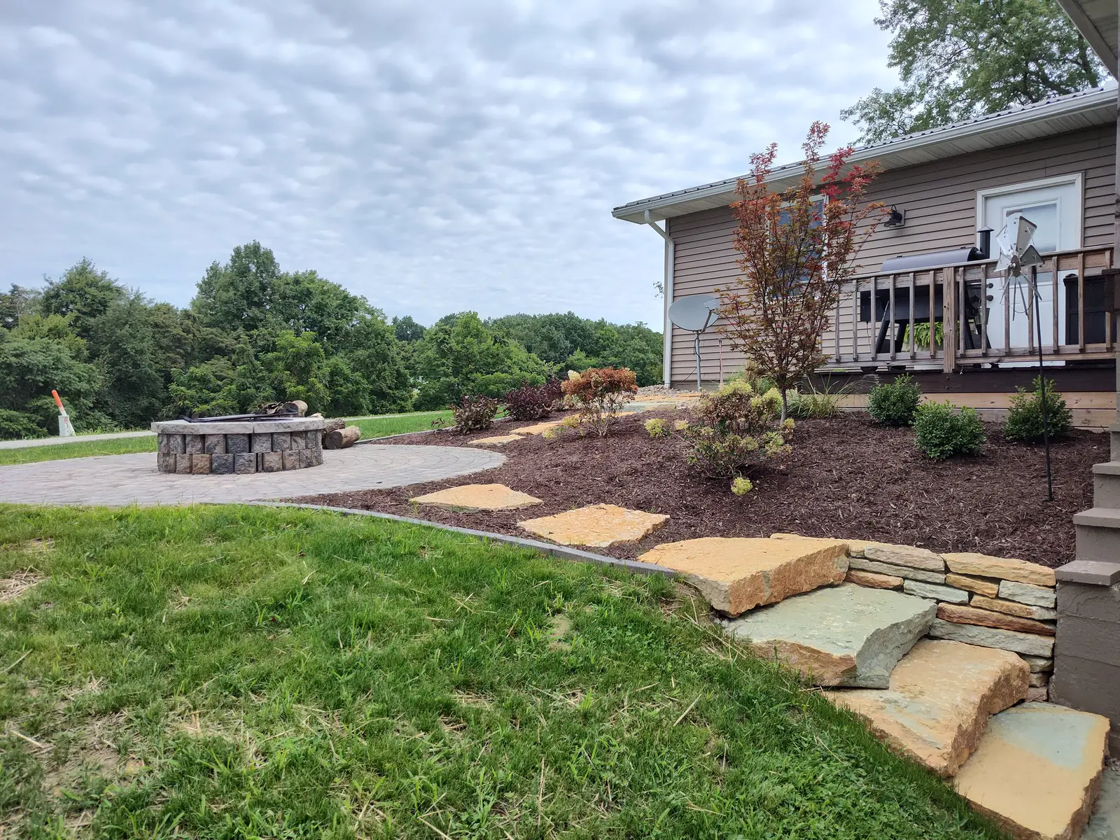 Fire pit destination connected by stone paths and new planting by Dave's Landscaping