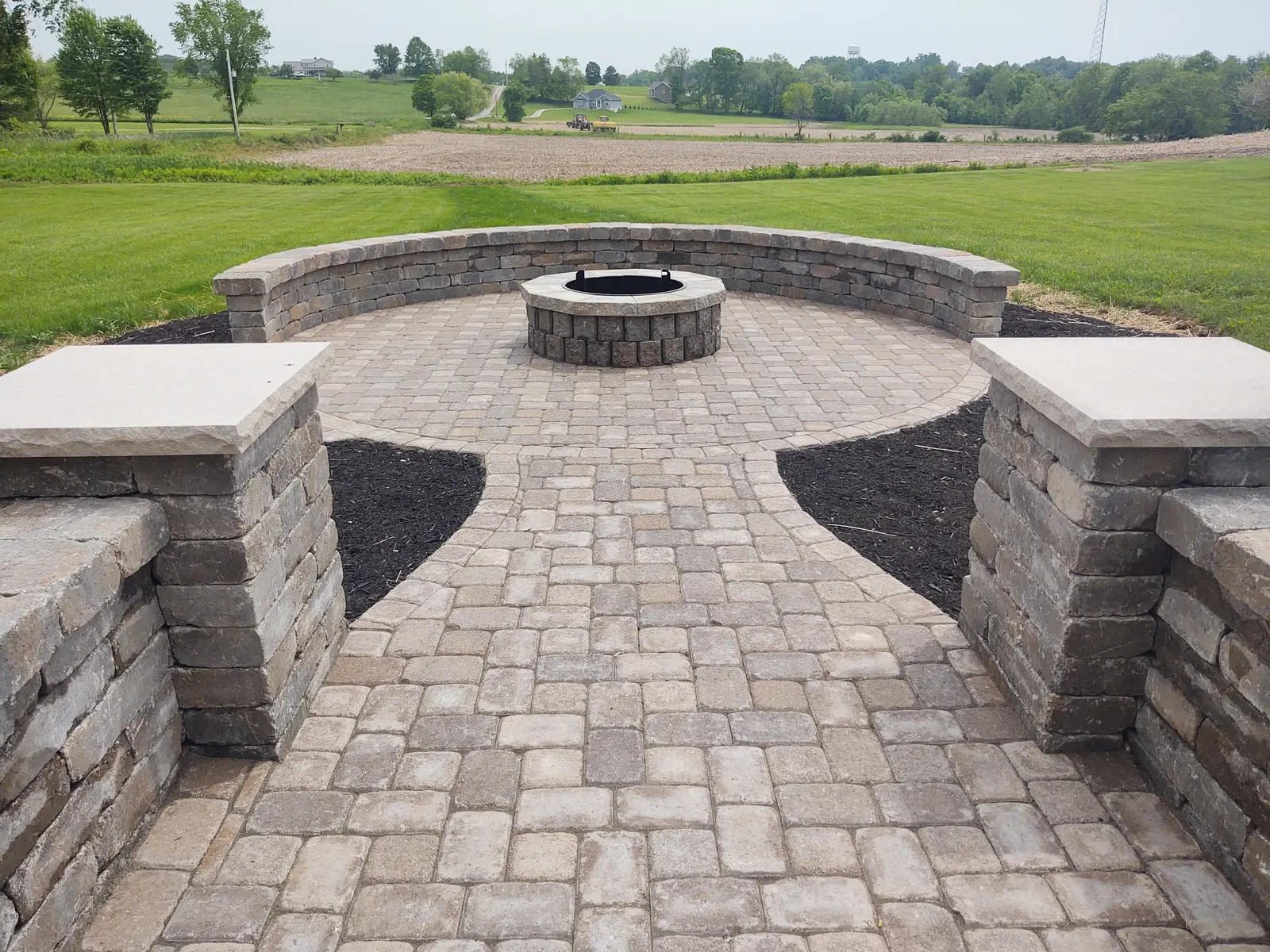 Paver path opening into a circular fire pit courtyard by Dave's Landscaping
