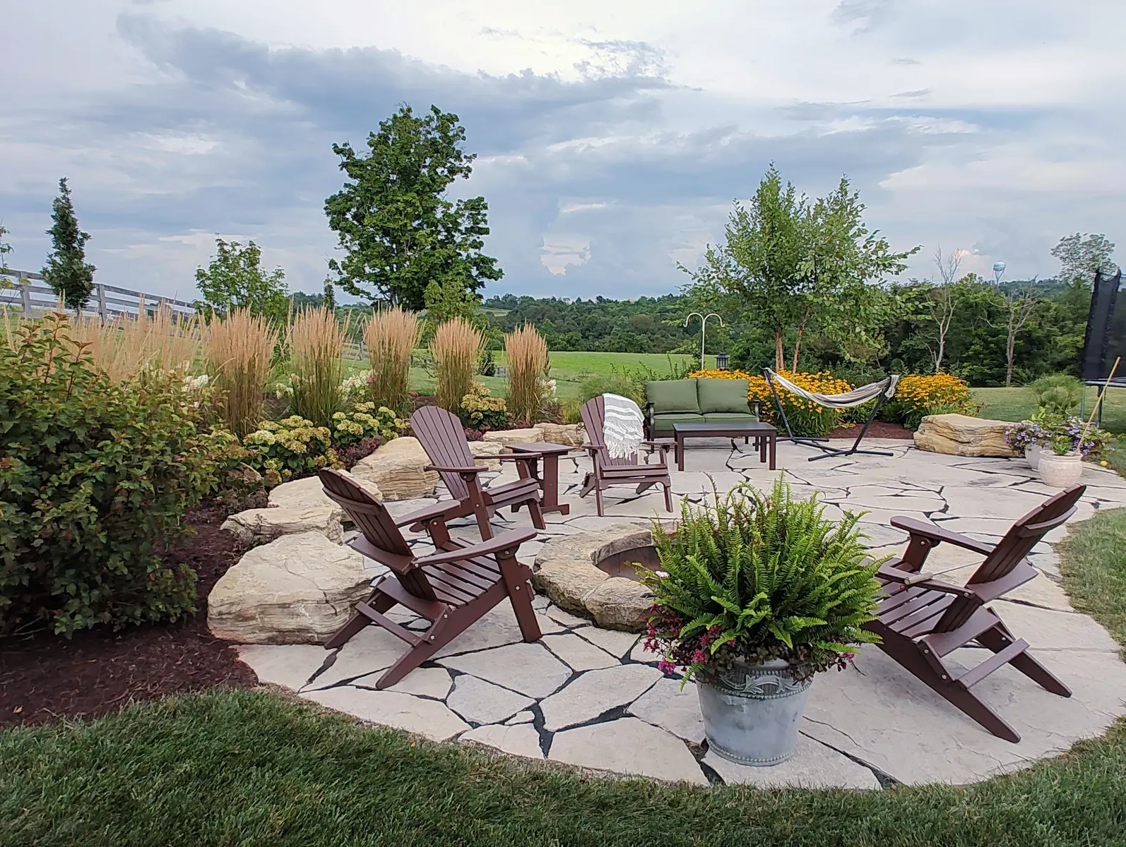 Flagstone gathering terrace with fire pit and ornamental grasses by Dave's Landscaping