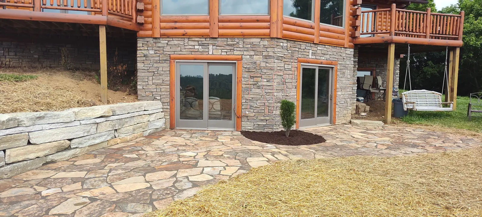 Natural flagstone terrace connecting a log home to the landscape by Dave's Landscaping
