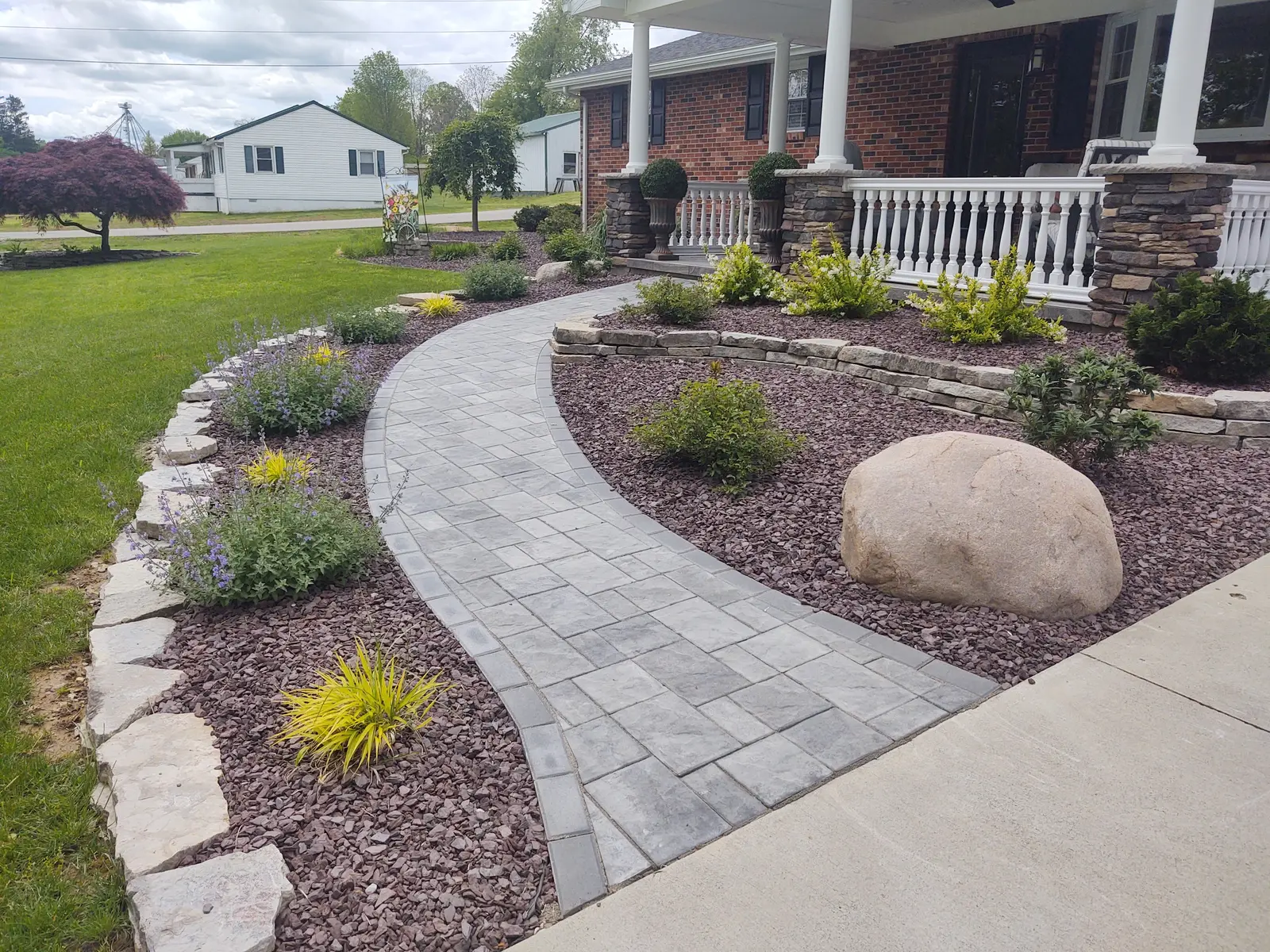 Elegant paver walkway winding through a finished front landscape by Dave's Landscaping