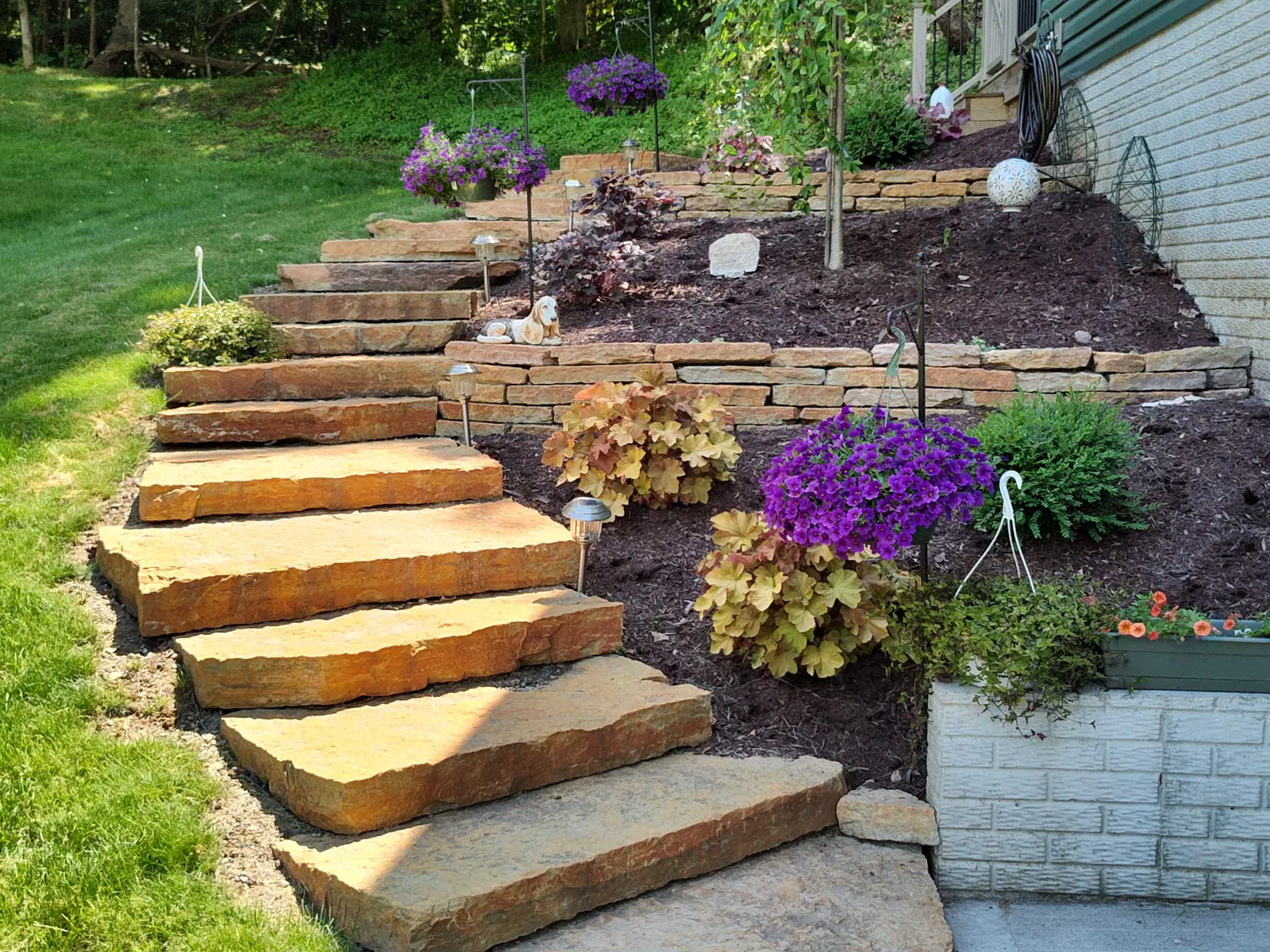 Natural-stone steps surrounded by flowering garden beds by Dave's Landscaping