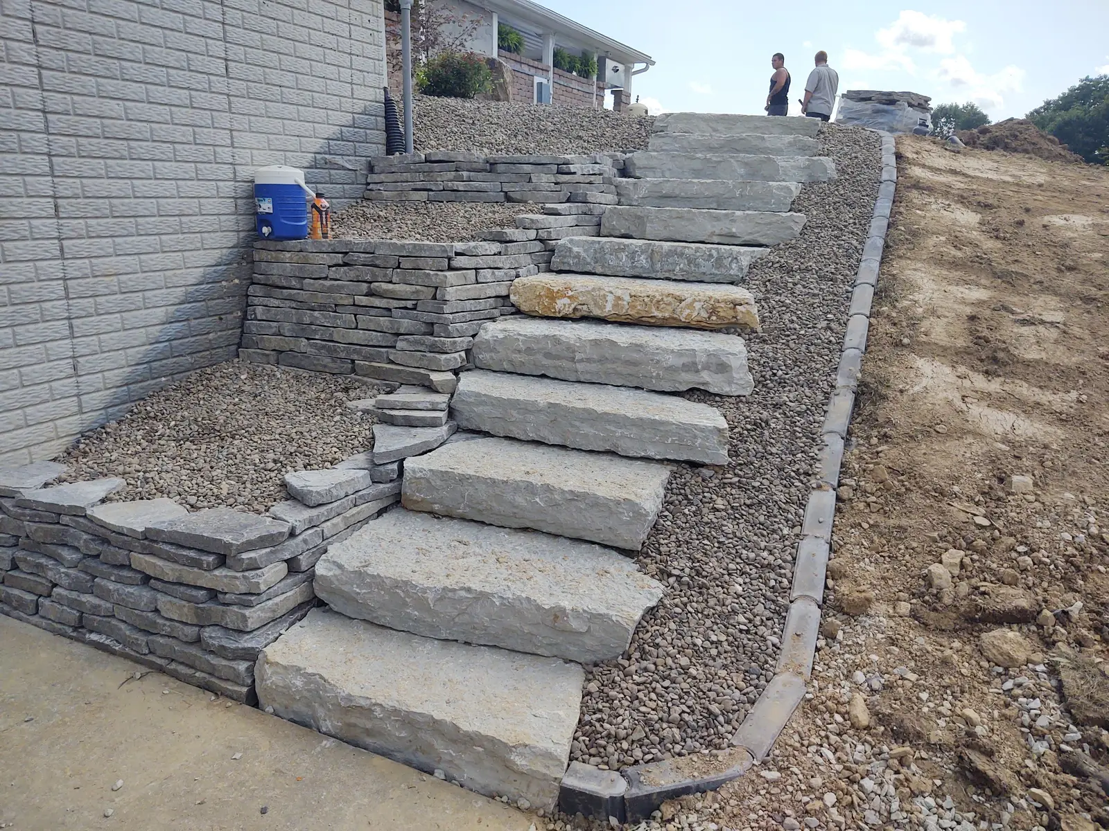 Large natural-stone steps built into a steep hillside by Dave's Landscaping