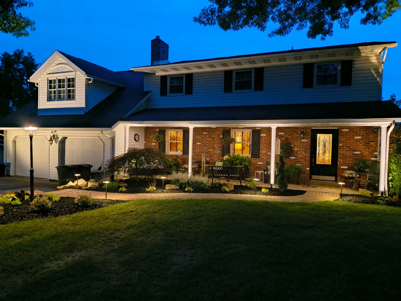 Warm architectural landscape lighting on a brick home by Dave's Landscaping