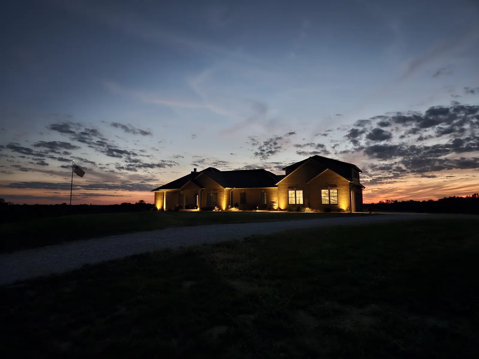 Warm landscape lighting welcoming guests at sunset by Dave's Landscaping