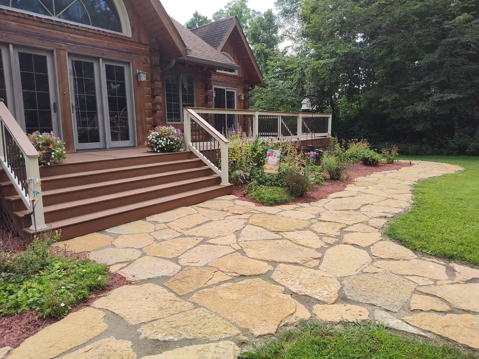 Flagstone walkway and garden beds at a woodland home by Dave's Landscaping