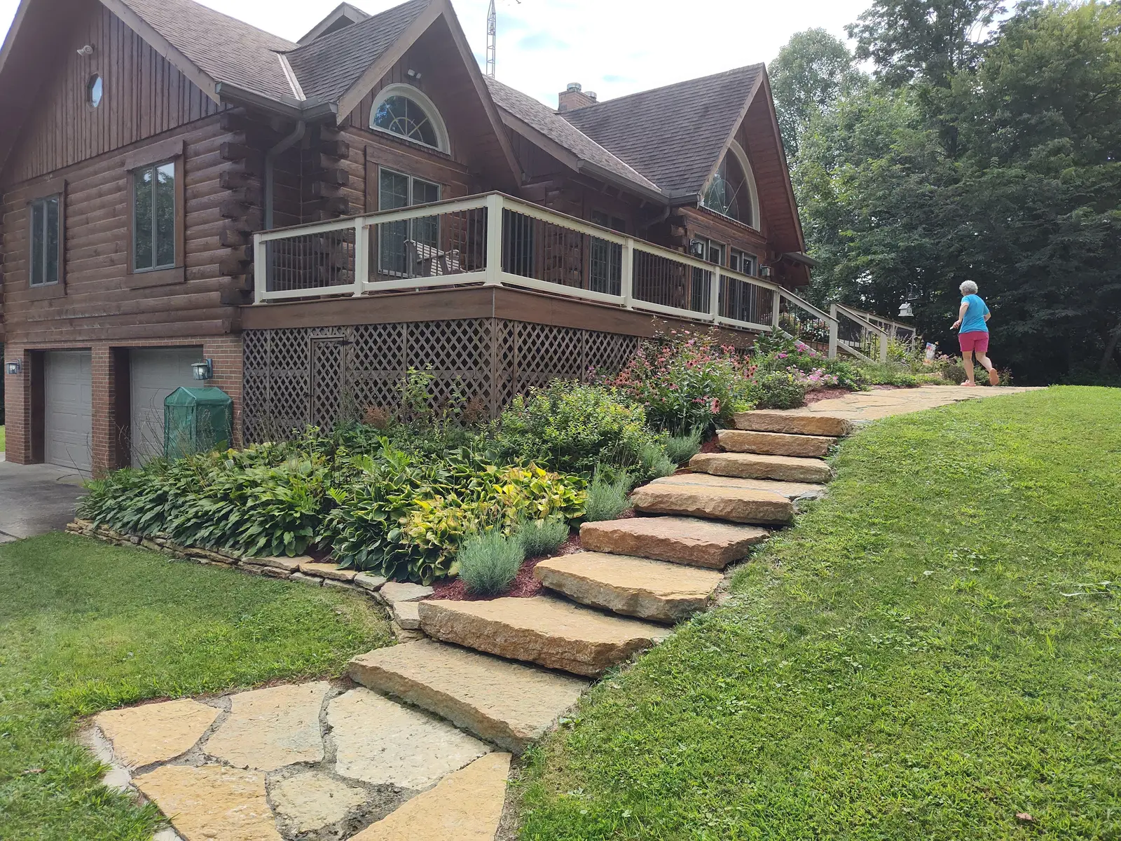 Wide view of natural-stone steps and planting at a log home by Dave's Landscaping