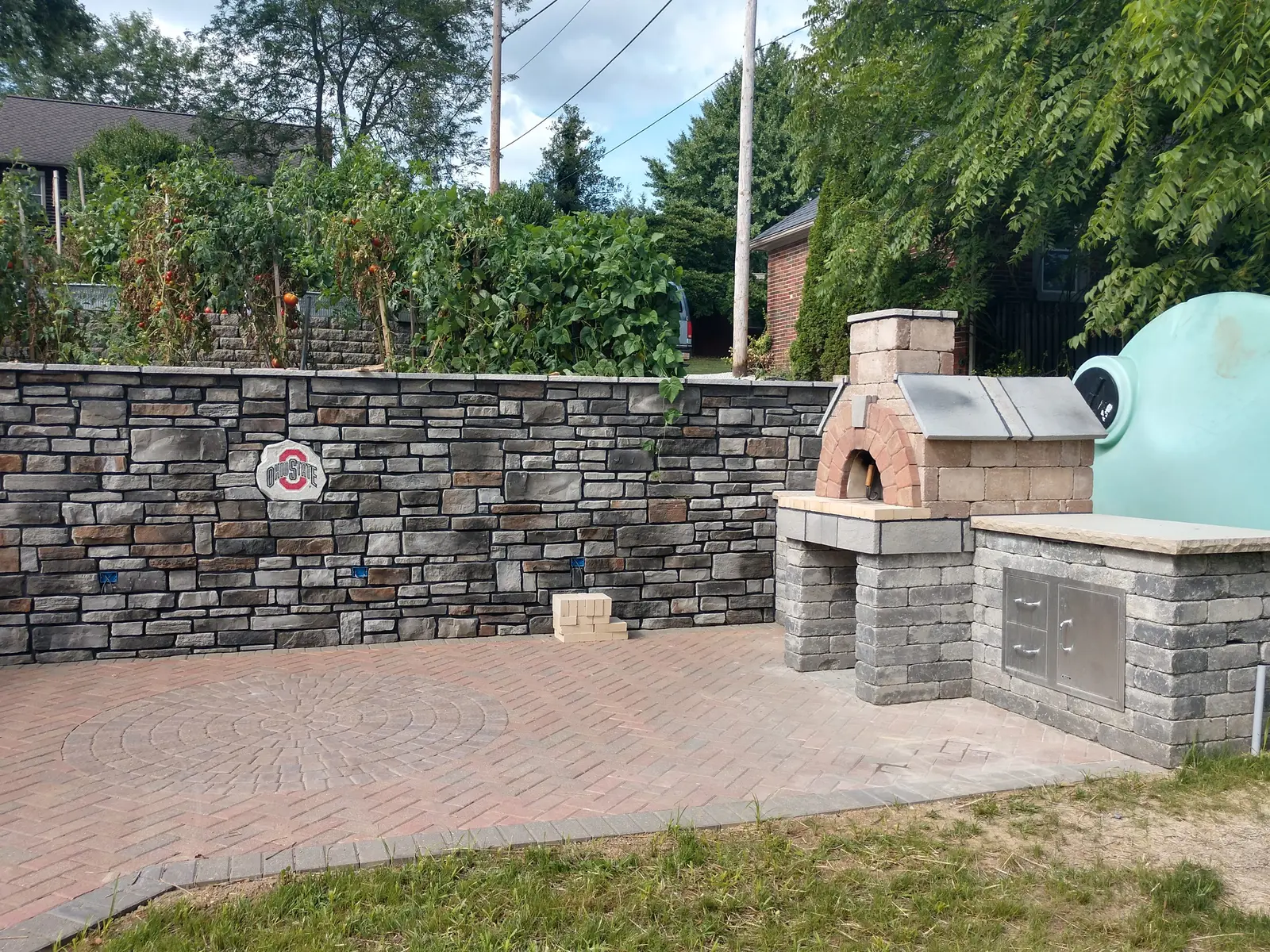 Outdoor pizza oven, seat wall, and brick patio by Dave's Landscaping