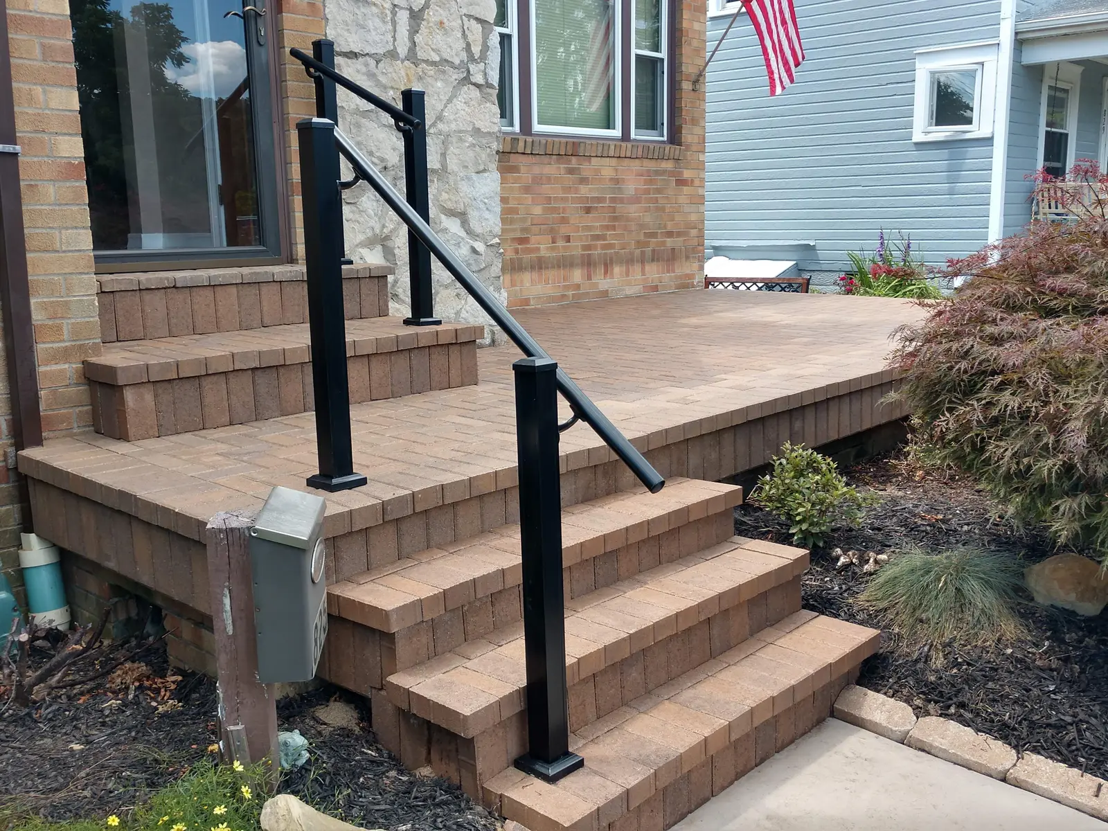 Paver steps and landing with clean black railings by Dave's Landscaping