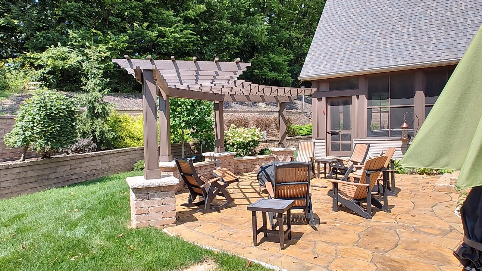 Pergola dining patio beside a lodge-style home by Dave's Landscaping