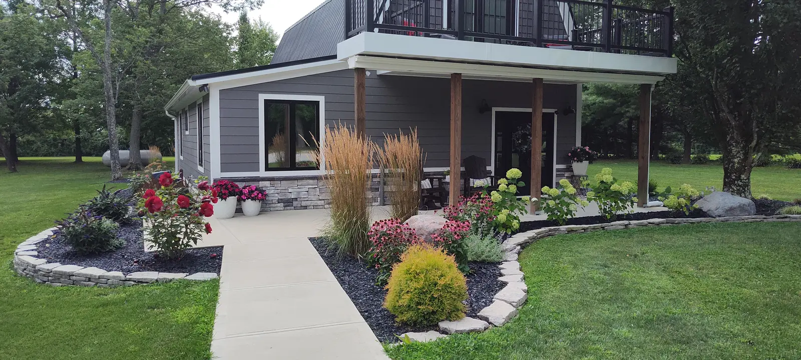 Curved backyard planting bed beside a modern addition by Dave's Landscaping