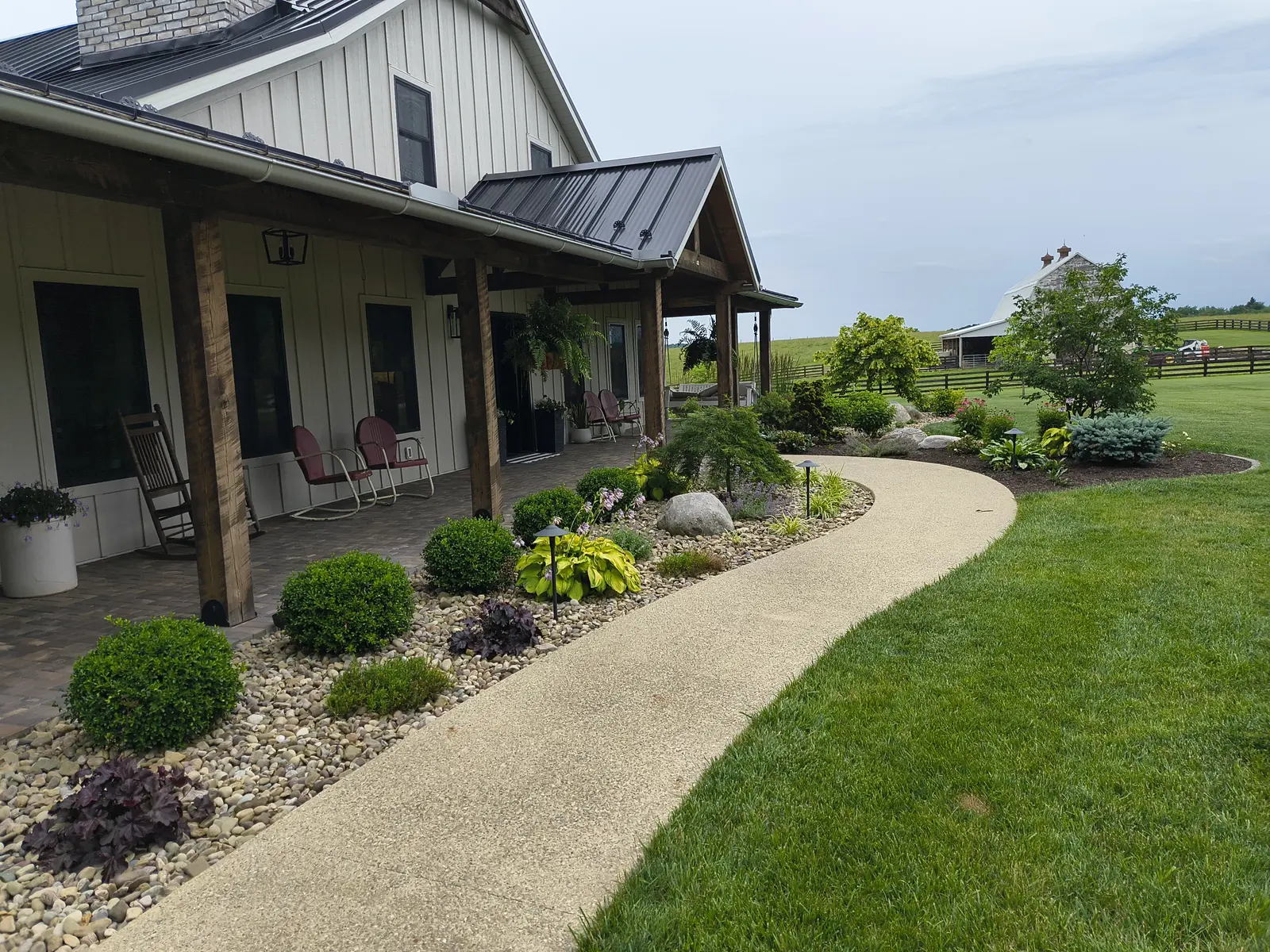 Curved walkway connecting a lush residential landscape by Dave's Landscaping