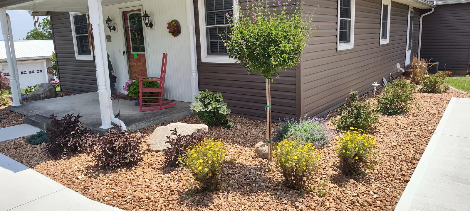 Colorful front-yard planting with stone accents by Dave's Landscaping