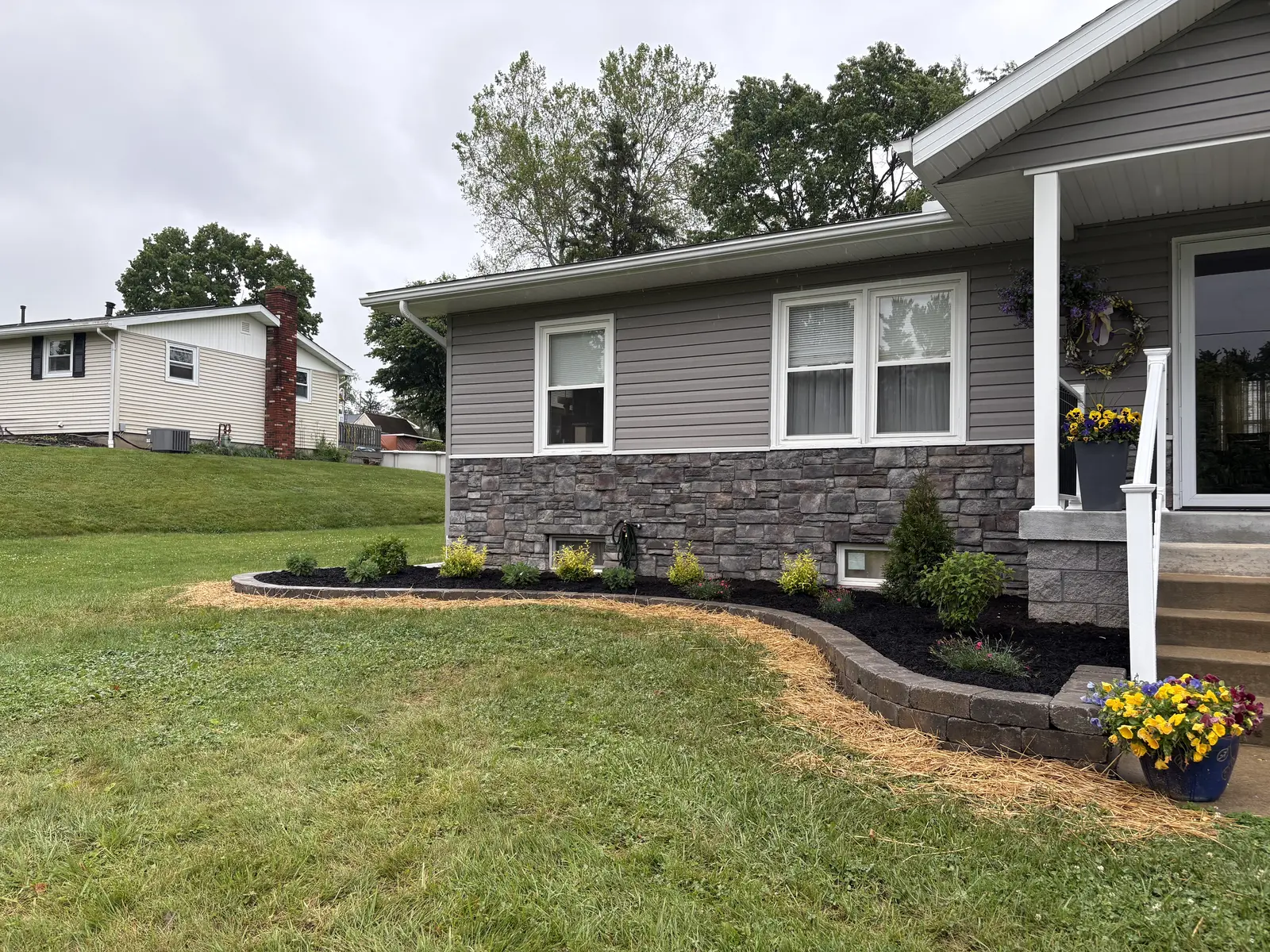 Fresh foundation planting and dark mulch at a renovated home by Dave's Landscaping