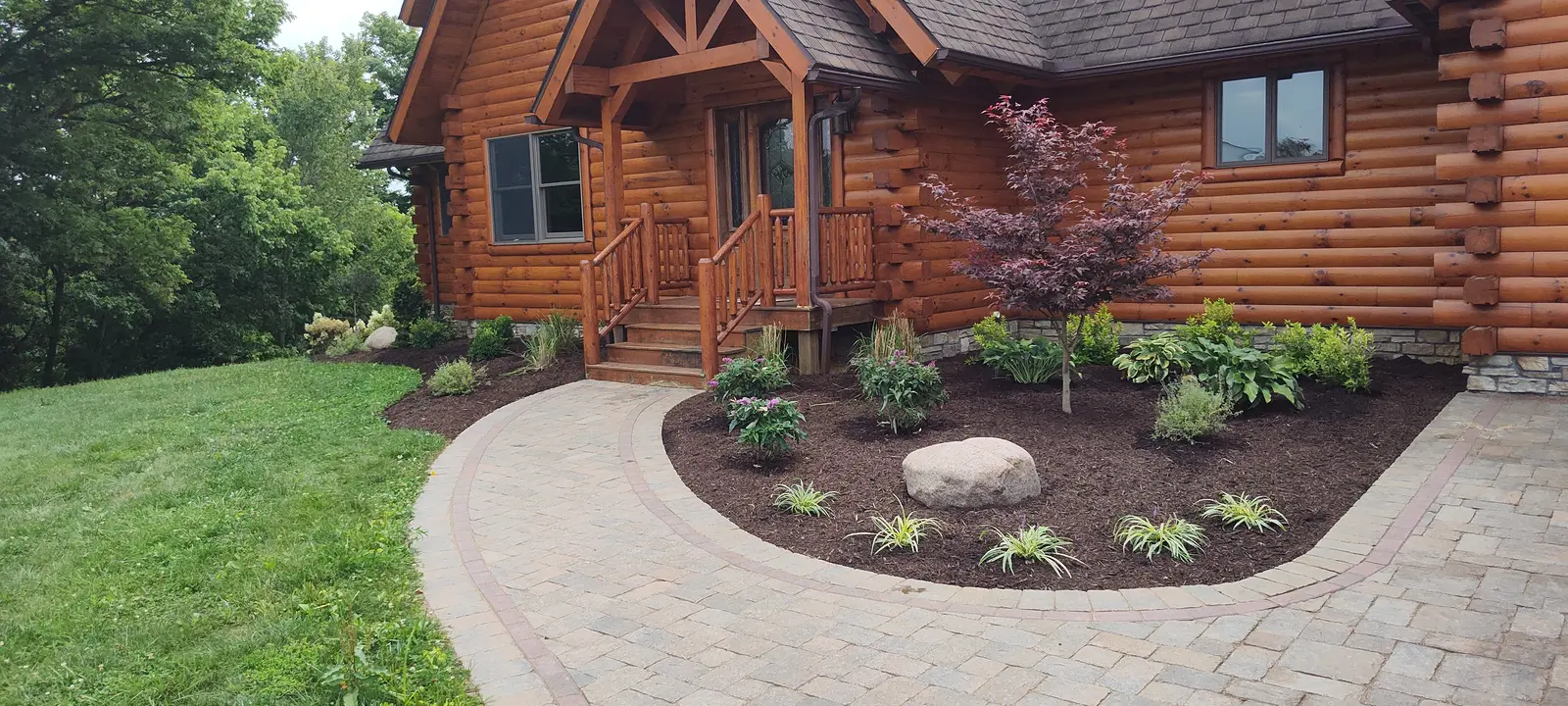 Curved walkway and ornamental planting at a log home by Dave's Landscaping