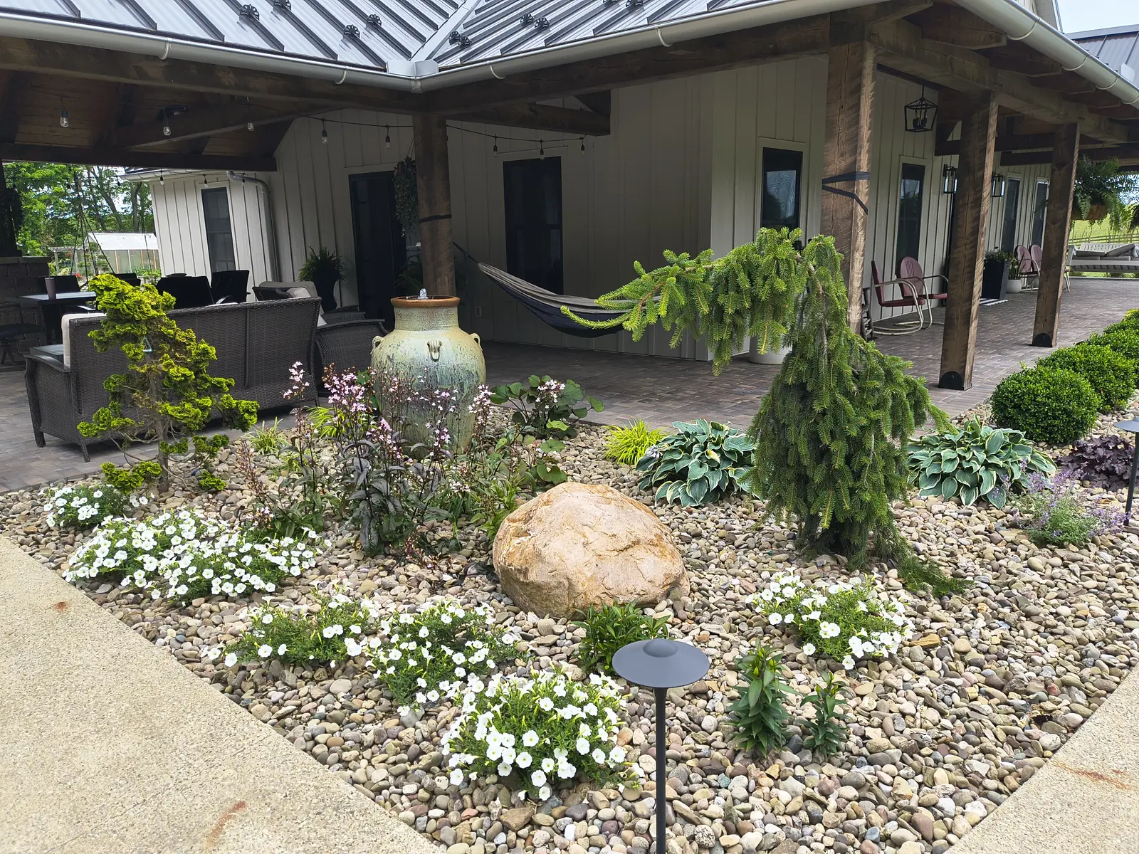 Detailed ornamental bed with stone and flowering groundcover by Dave's Landscaping
