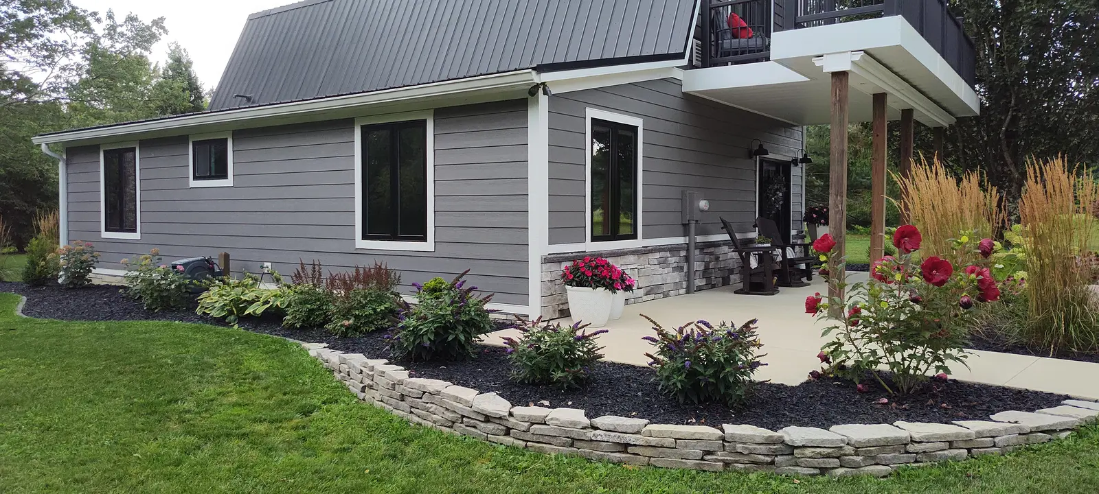 Stone-edged planting bed with flowering perennials by Dave's Landscaping