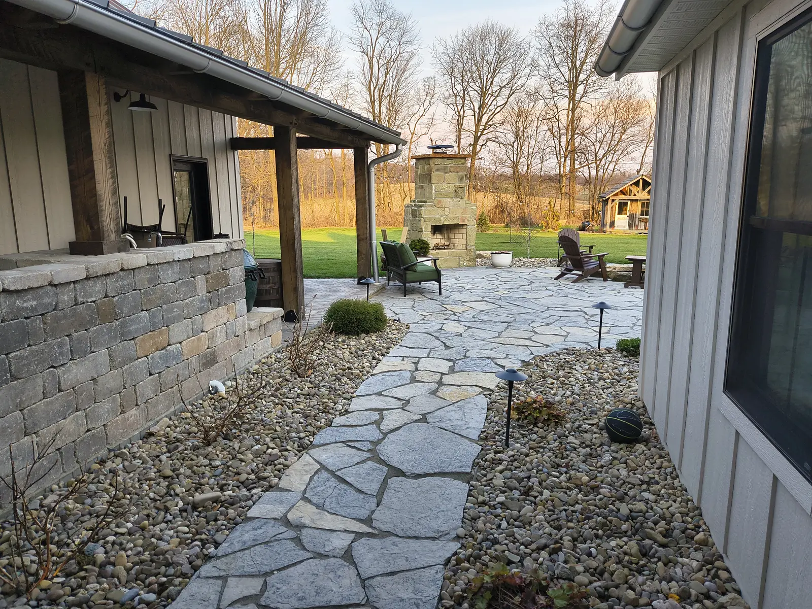 Large flagstone courtyard with integrated outdoor kitchen by Dave's Landscaping