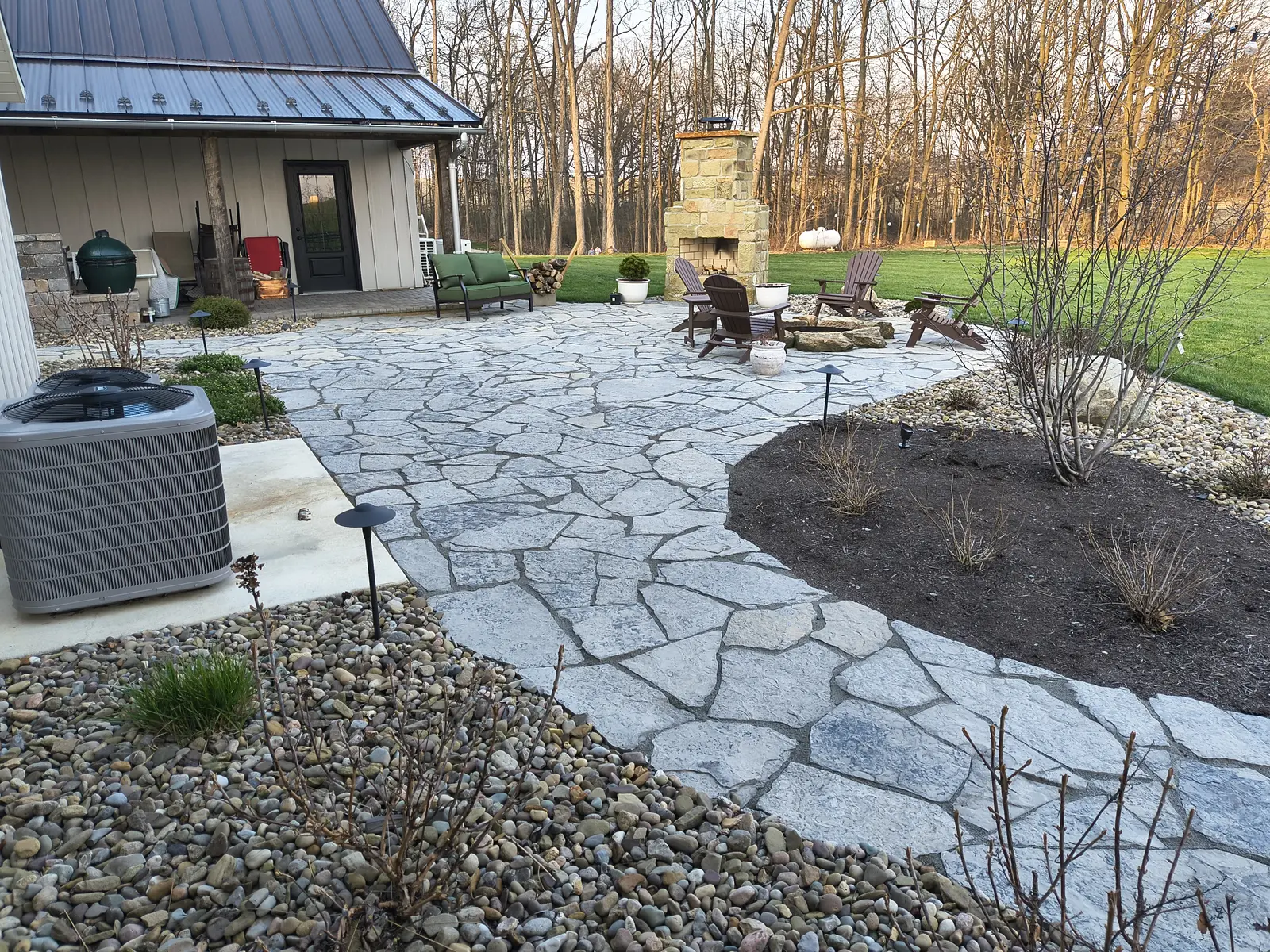 Premium flagstone patio with fireplace and layered planting by Dave's Landscaping