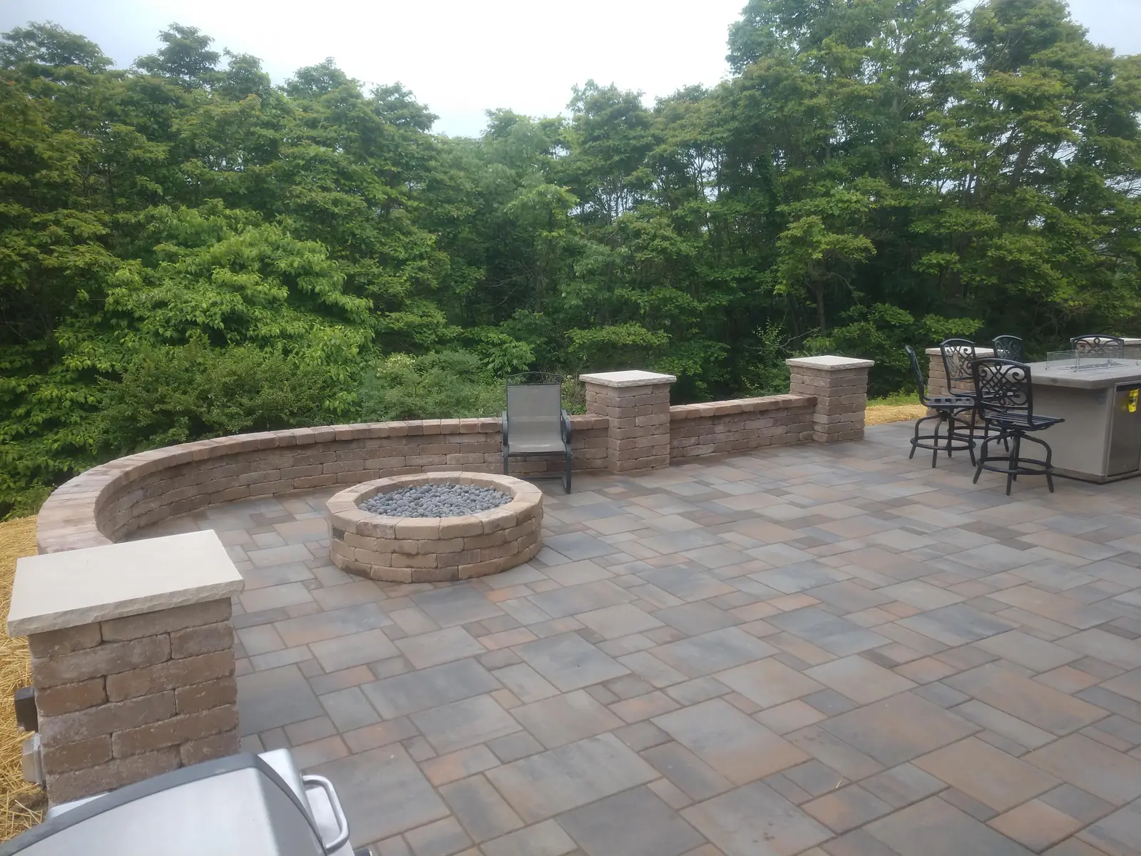 Elevated paver terrace with fire pit and masonry columns by Dave's Landscaping