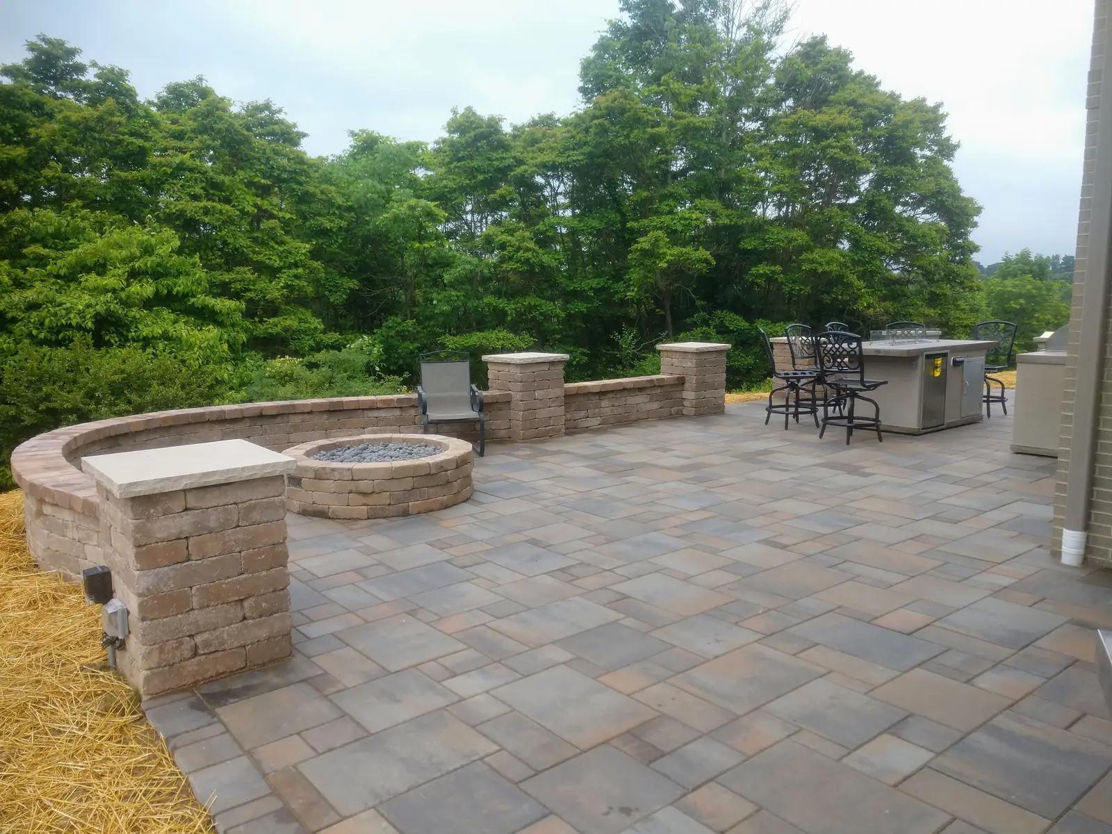 Wide paver terrace with fire pit and wooded views by Dave's Landscaping