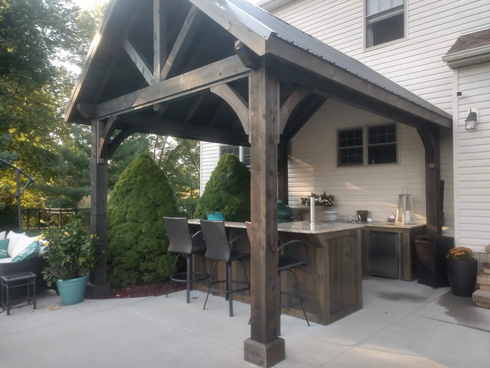 Wide view of a timber pavilion, grill, and lounge area by Dave's Landscaping