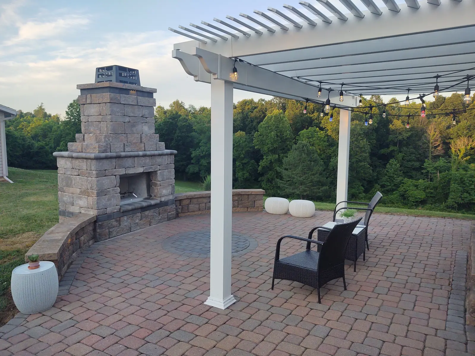 White pergola and outdoor fireplace overlooking the landscape by Dave's Landscaping