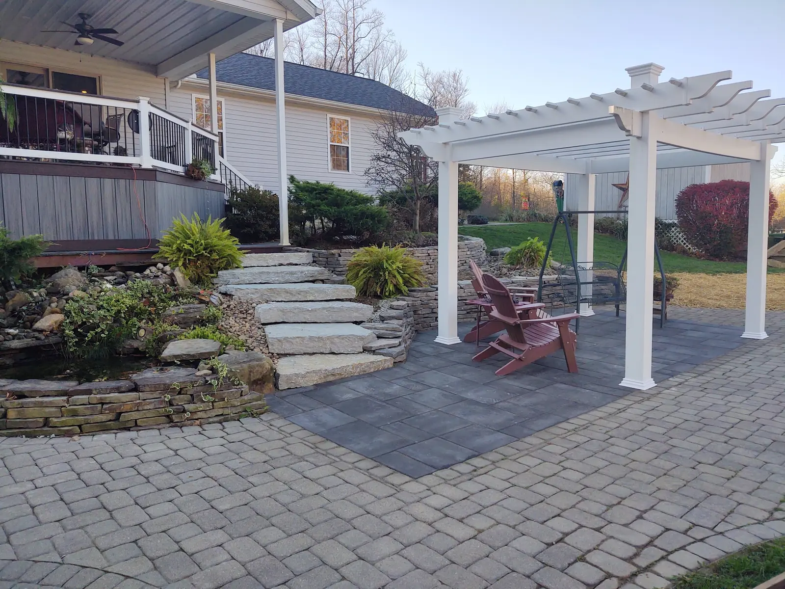 White pergola, paver patio, and natural-stone steps by Dave's Landscaping